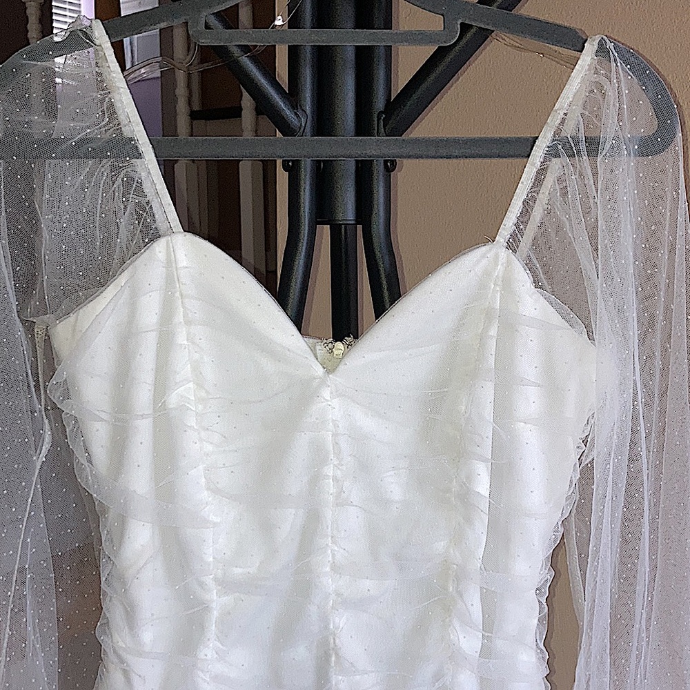 White bodysuit with dotted mesh sleeves.